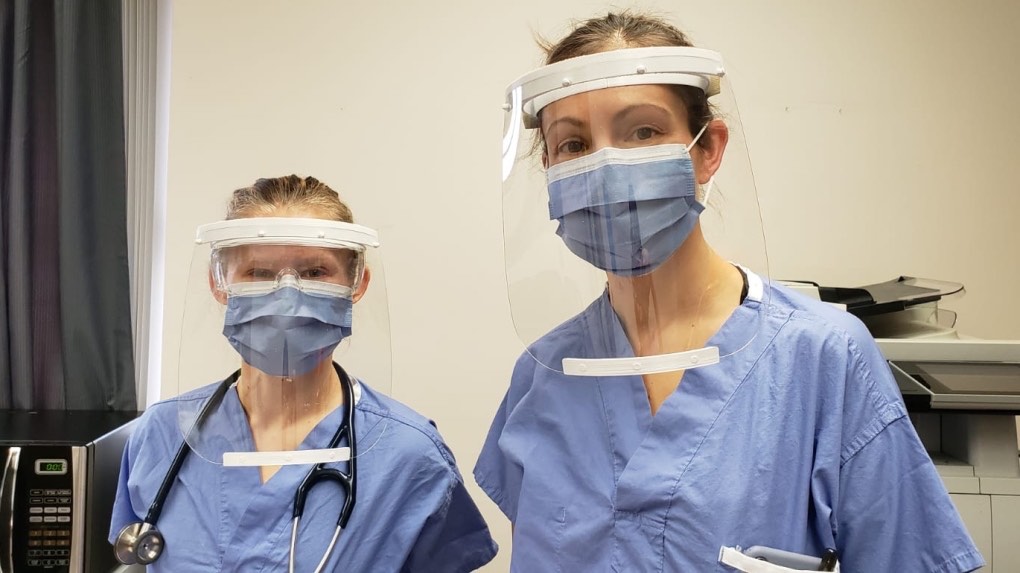 Two health professionals wearing face masks and face shields